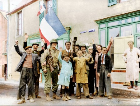 1944年6月12日,法国圣奥诺里讷镇的民众在三色旗下欢迎三名盟军(美国)大兵。(Courtesy of Marina Amaral)